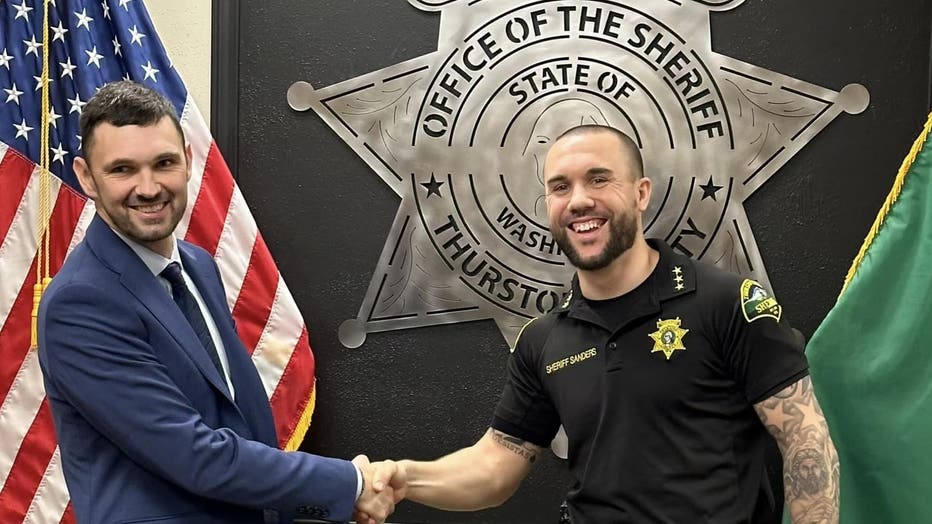 sheriff sanders shakes hands with deputy burbank