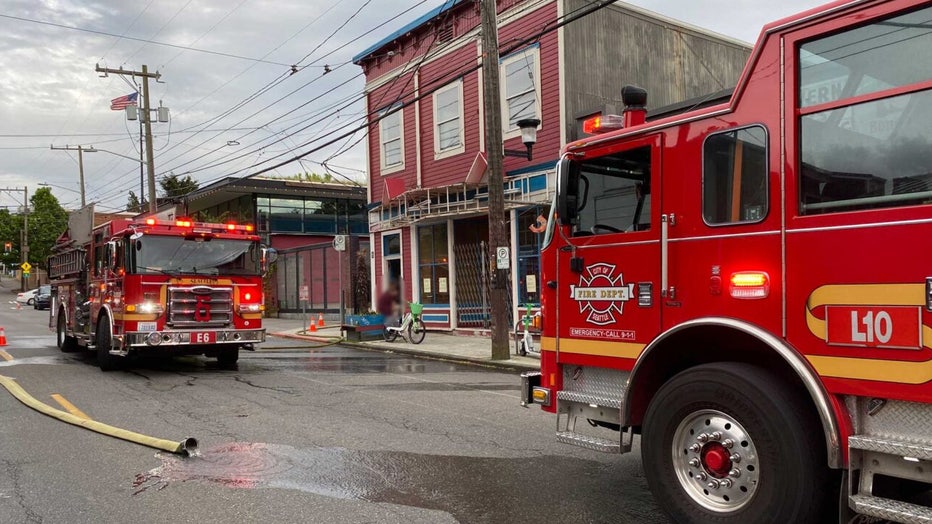 photo of two seattle fire department firetrucks responding to an apartment fire in Seattle's Central District. A hose is seen laying on the street still spraying water.