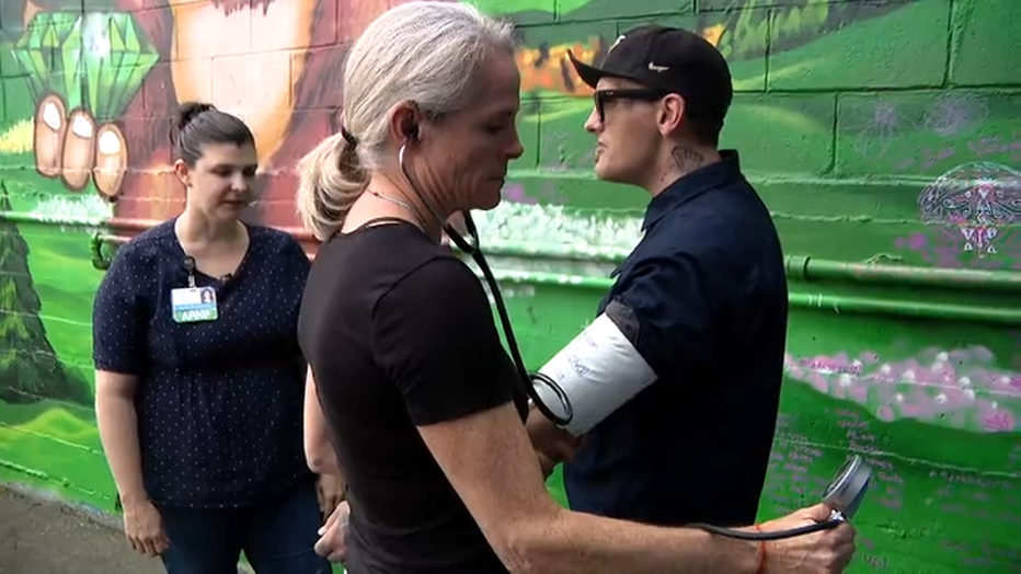 nurse takes a man's blood pressure on the streets of seattle