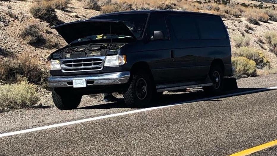 black van on side of road with hood up