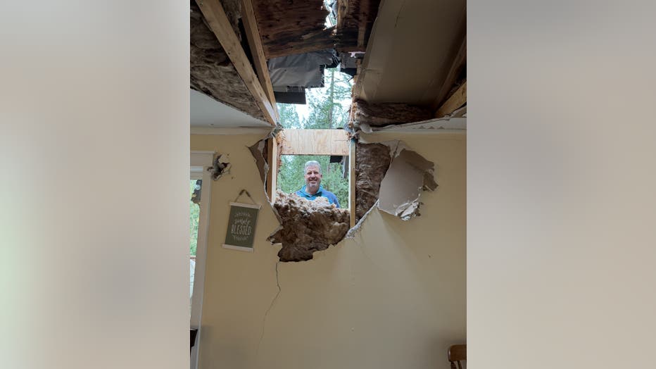 Shea smiles through a hole in his wall caused by a falling tree