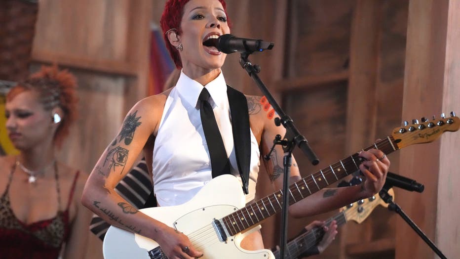 halsey performs on stage with a guitar