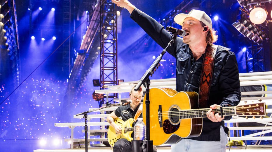 morgan wallen singing on stage with a guitar