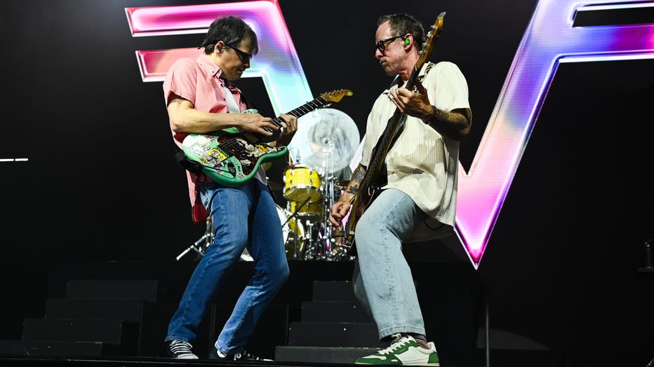 rivers cuomo and scott shriner of weezer play on stage