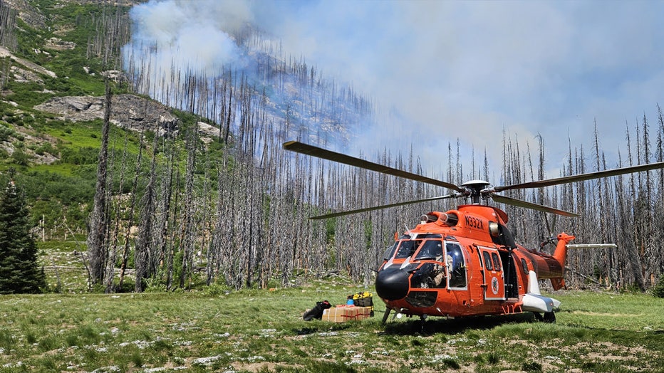 A helicopter uses the only secure landing zone within this area of the Glacier Peak Wilderness to bring additional rappelers and hotshots to contain the Pomas Fire on June 15, 2025. The fire is burning in dense dead and down timber from the 2015 Wolverine Fire.