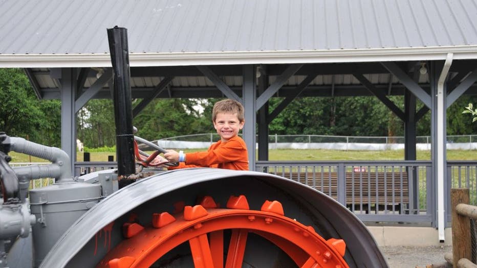a kid sits on a gigantic tractor