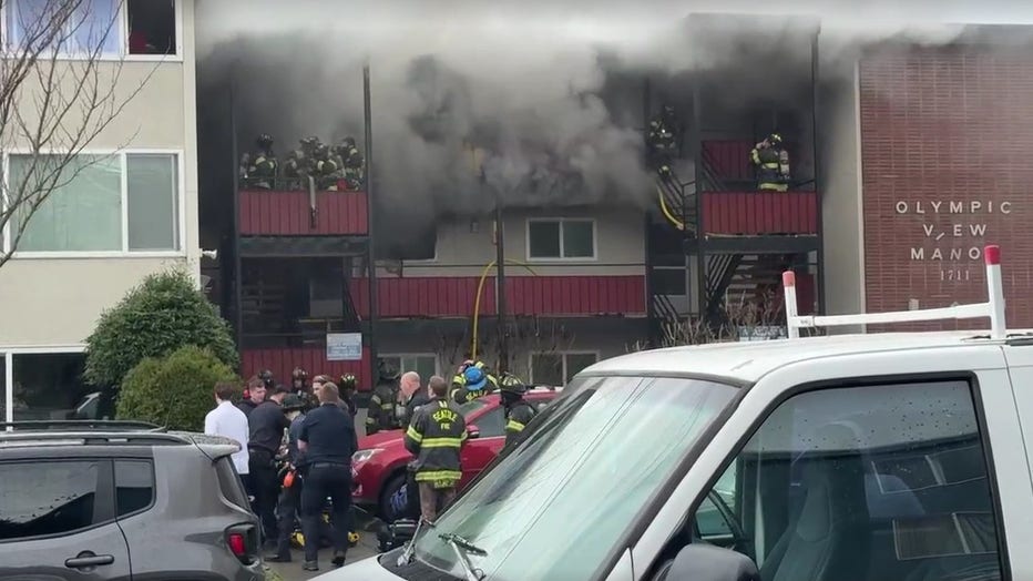 firetrucks are parked outside of a smoky apartment building on fire in beacon hill seattle