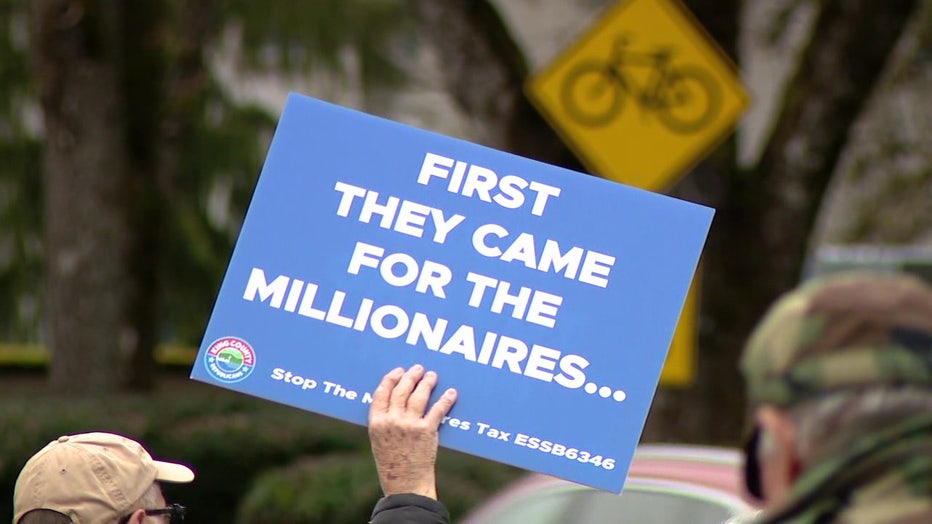 protester holds up sign reading 'first they came for the millionaires' against the proposed millionaires tax during a rally in olympia, washington