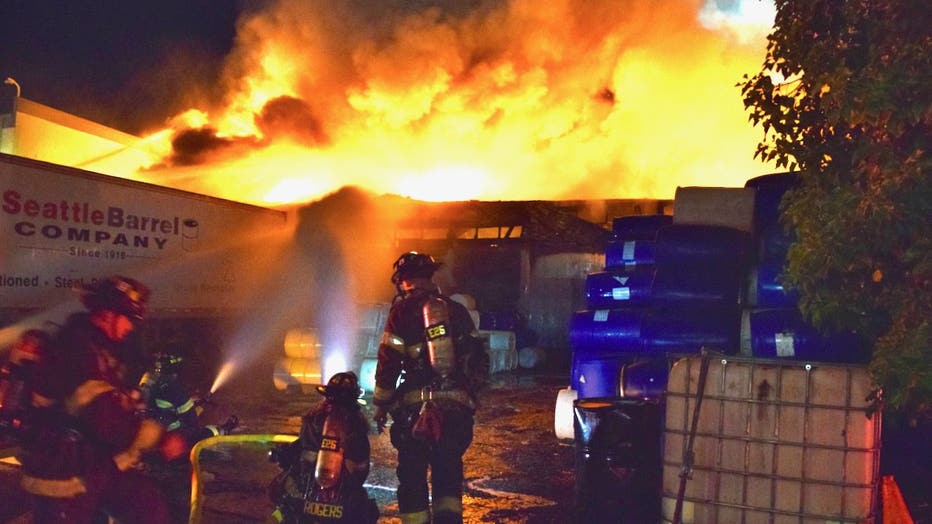 A three-alarm commercial warehouse fire broke out in Seattle's Industrial District early Wednesday morning, drawing more than 100 emergency personnel to the scene. Crews fought the flames defensively due to unidentified barrels found near the building, prompting officials to issue a shelter-in-place advisory for nearby residents. No injuries were reported, and investigators are working to determine what sparked the blaze after the warehouse roof collapsed.