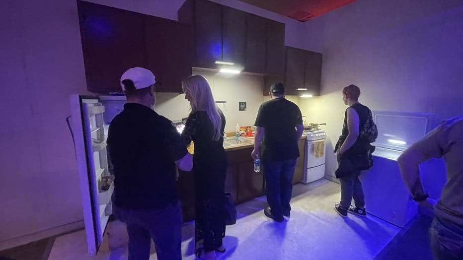 Visitors look into a sink and refrigerator at a mock-up of Jeffrey Dahmer's apartment. 