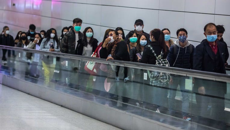 People wearing facemasks ride a travelator inside a train station on the second day of the Lunar New Year of the Rat in Hong Kong on January 26, 2020, as a preventative measure following a coronavirus outbreak which began in the Chinese city of Wuhan. - Hong Kong on January 25 declared a mystery virus outbreak as an 