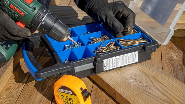 Close up of man selecting screw for cordless screwdriver.